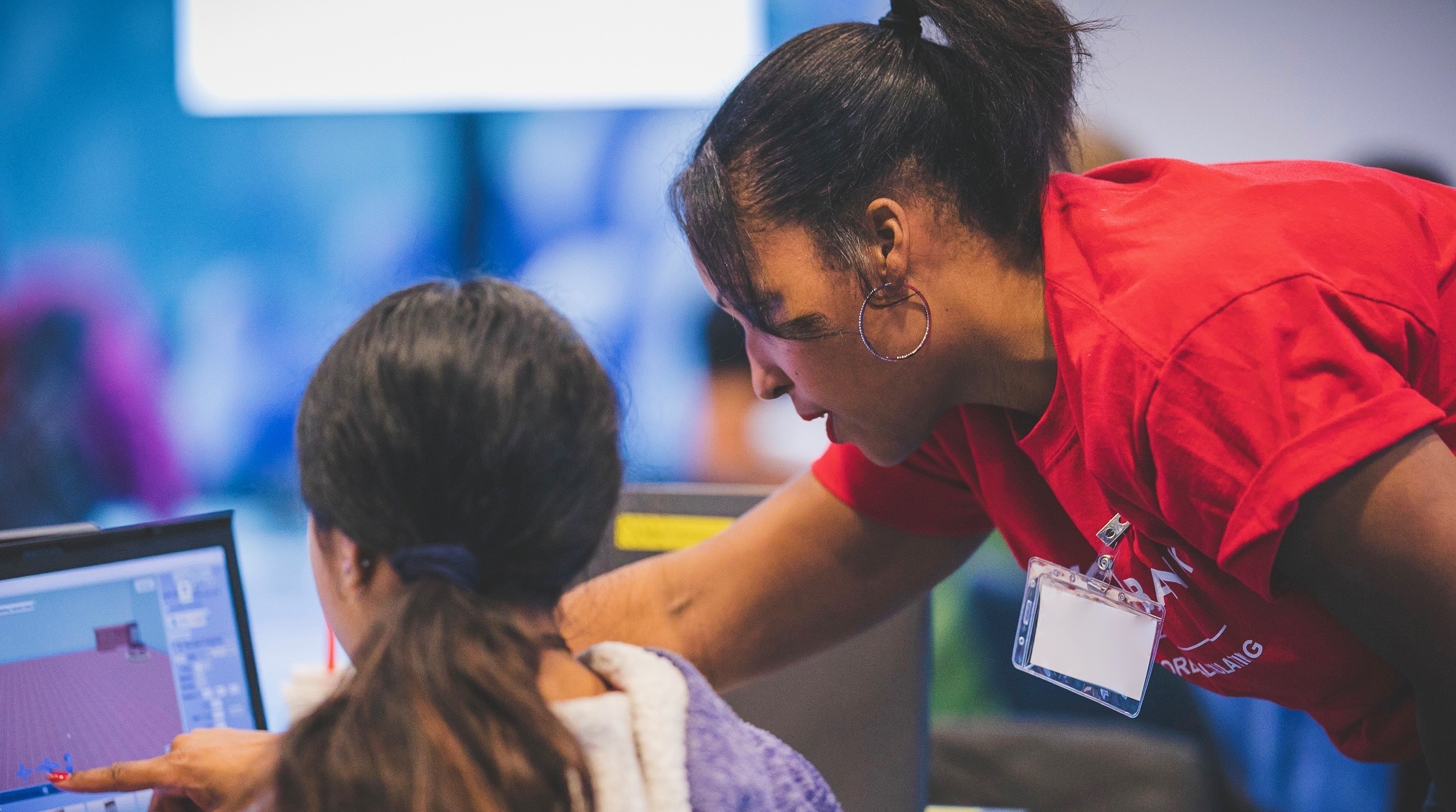 A Maydm instructor helps a student with a program during a summer workshop.